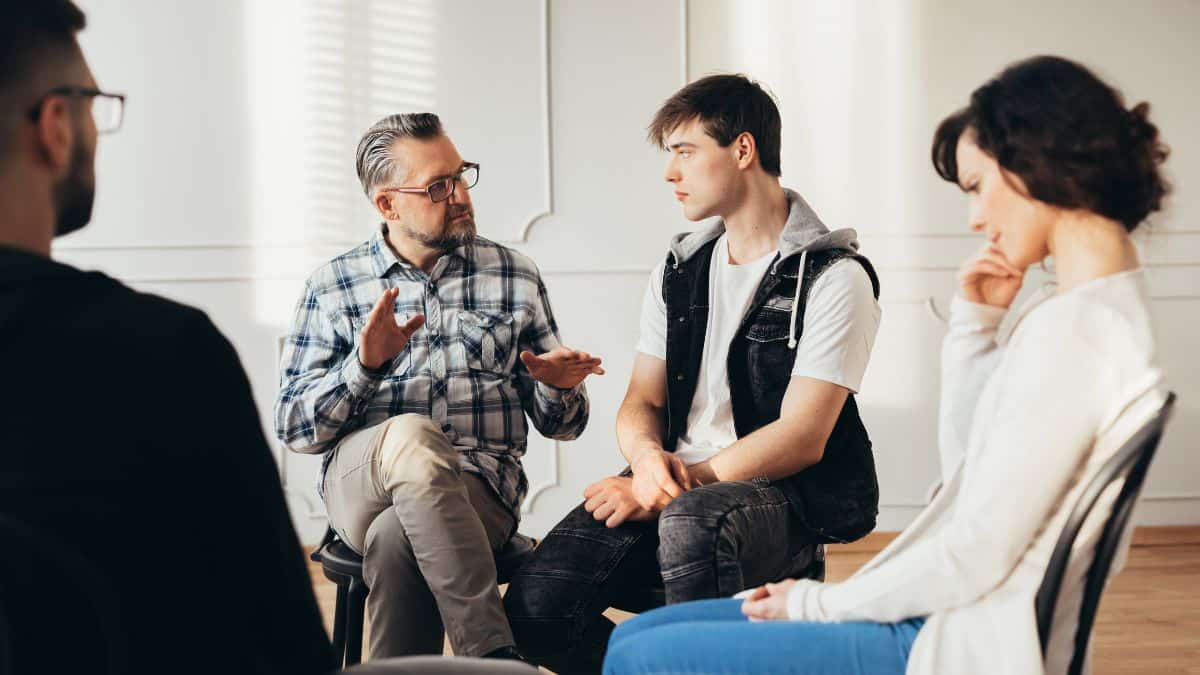 A therapist talking to individuals during 12-step education in California.